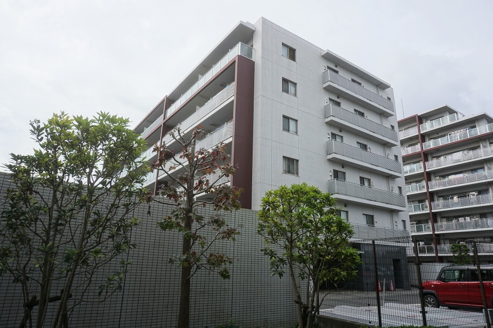 空のブルート樹のグリーンに映えるホワイトを基調としたカラーリング。バルコニー枠のワインレッドカラーやガラス手すりがアクセントとなっています。